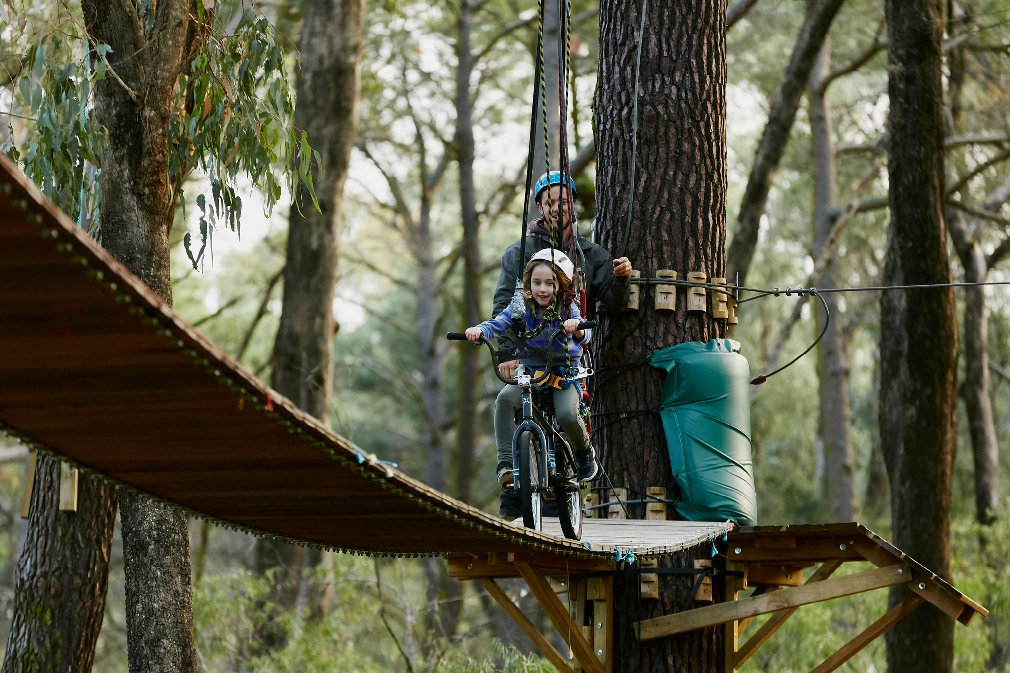 Child cycling across a wooden bridge at Forest Adventures