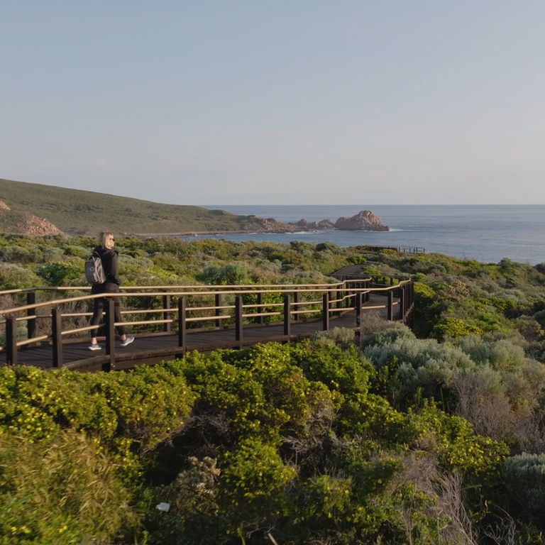 A person walking along a boardwalk pathway to Sugar Loaf Rock