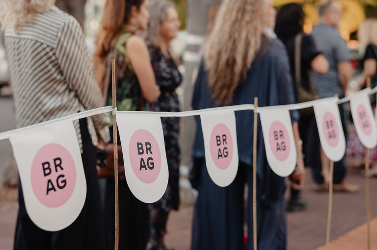 People queuing in a line behind BRAG branded bunting.
