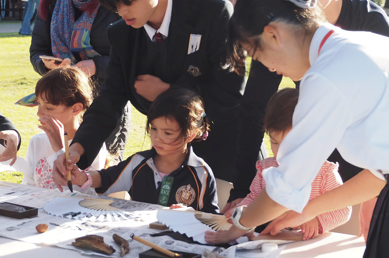 Children learning calligraphy with visiting Japanese students