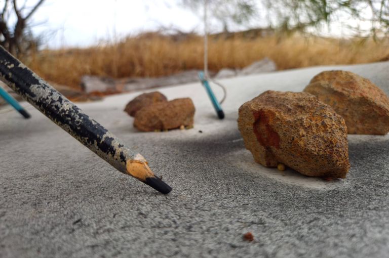 Pencil drawing on paper next to rocks