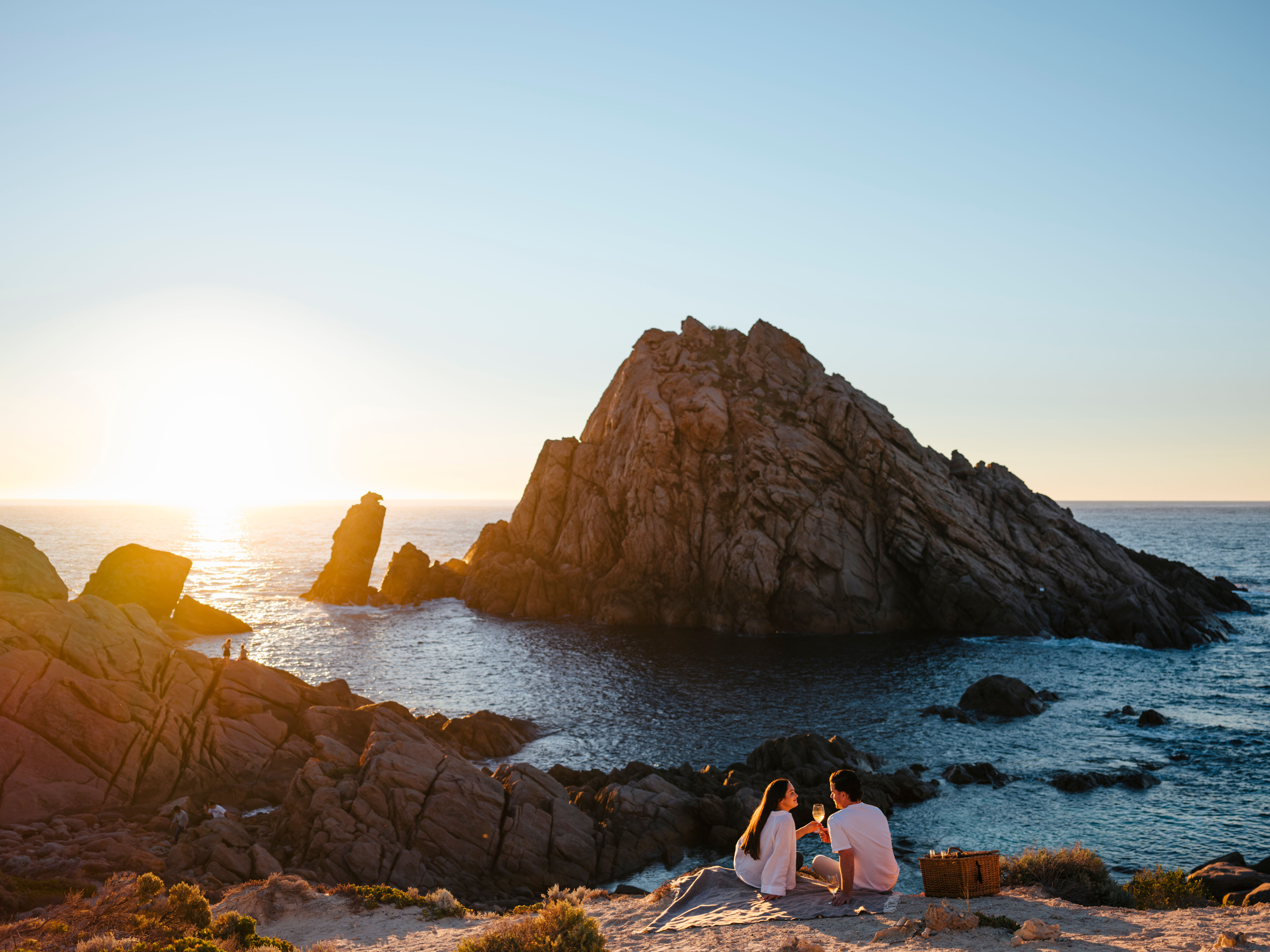 Photo of couple having a wine watching the sun set behind Sugarloaf Rock