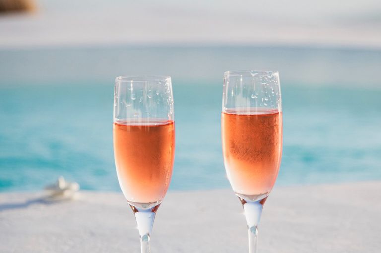 Photo of two glasses of sparkling wine on backdrop of blue ocean.