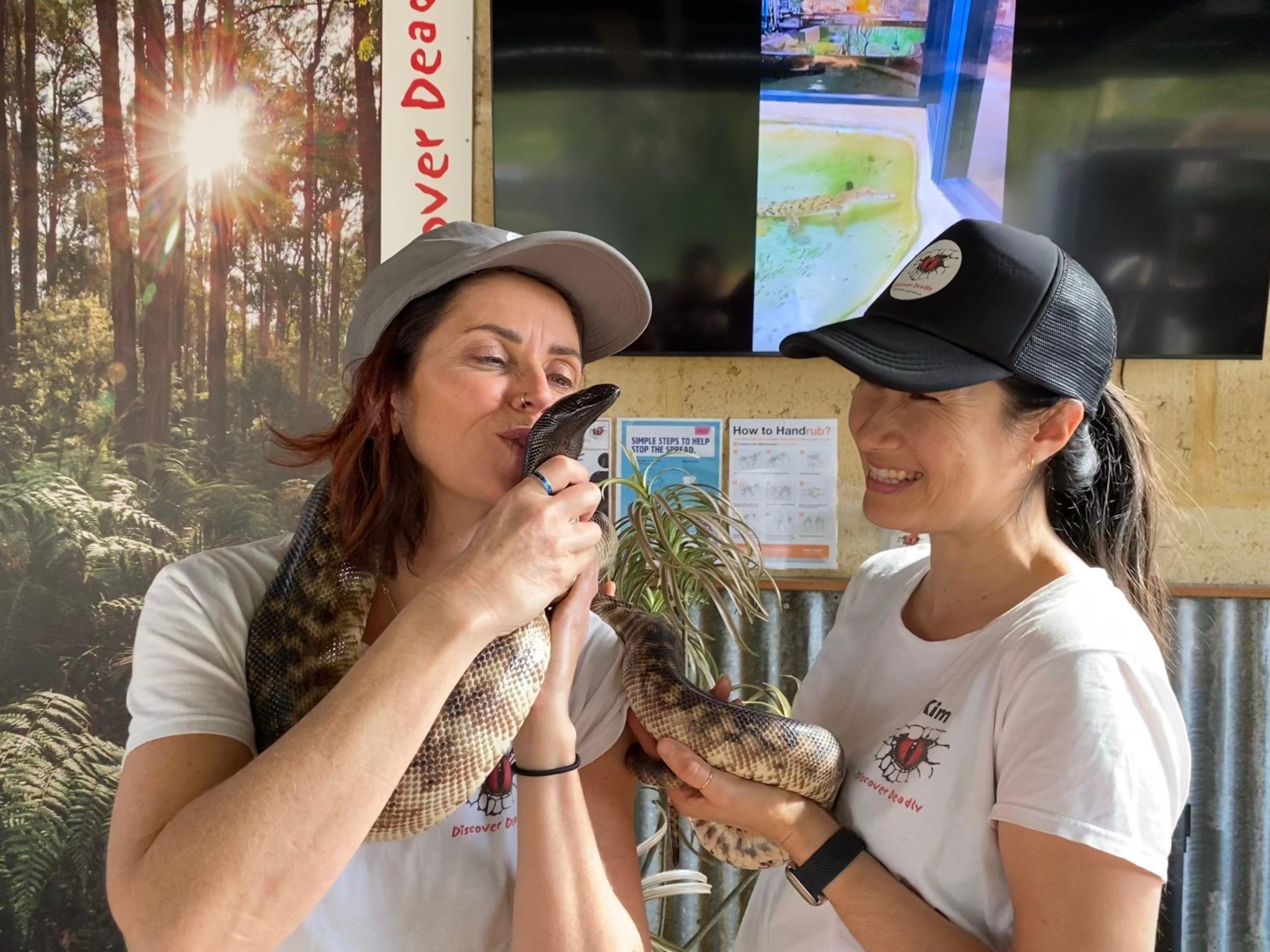 A photo of two women holding a python