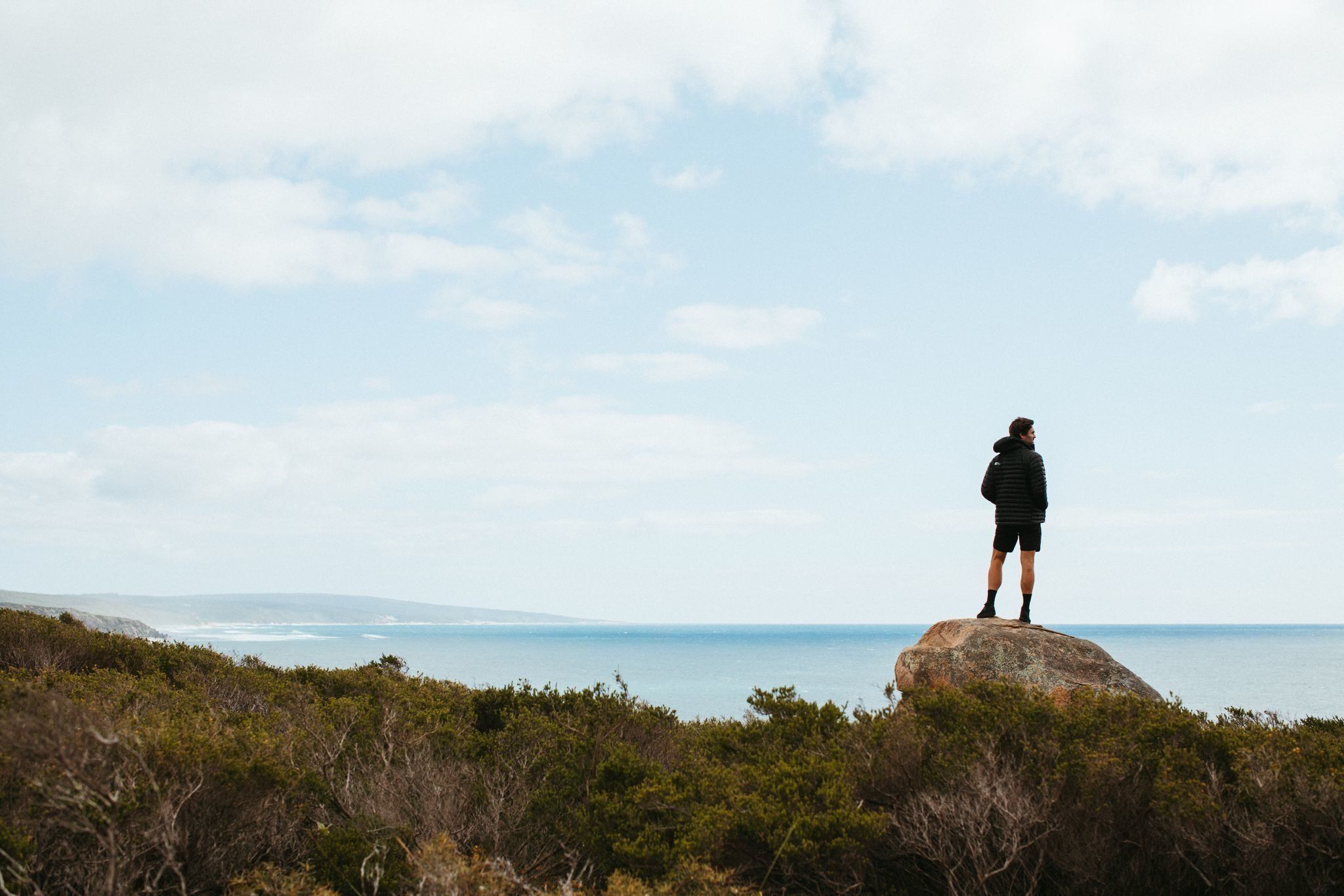 Ryan standing on a rock looking out at the ocean. Margaret River Brand Shoot. Credit Ryan Murphy