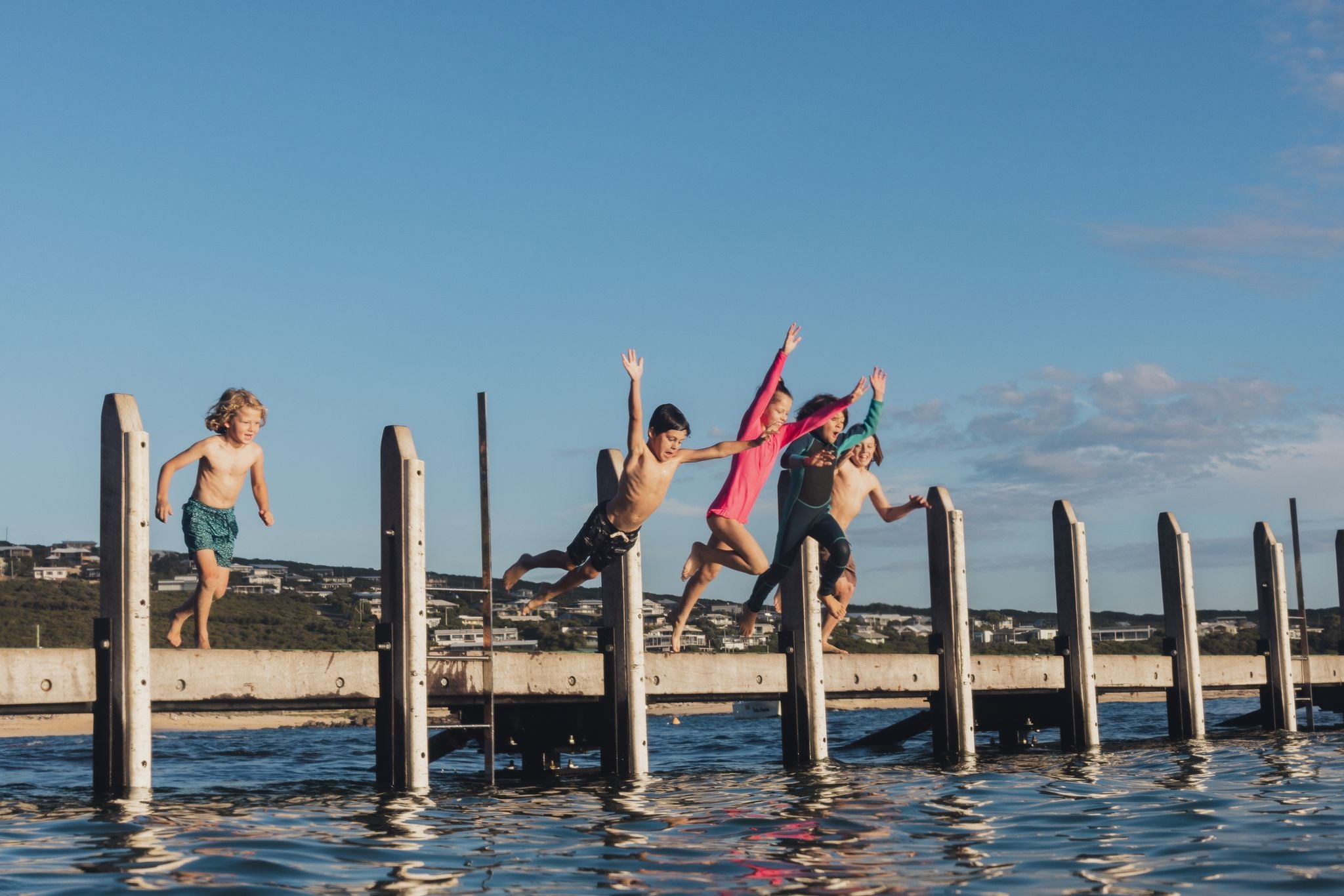Kids jumping off a jetty in summer. Credit Lewis French