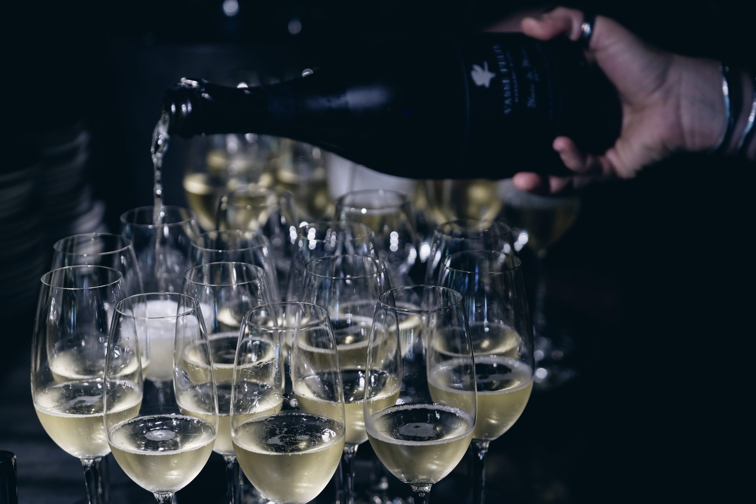 Sparkling wine is being poured into a group of wine glasses