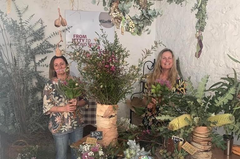 Two women in a room surrounded by flowers