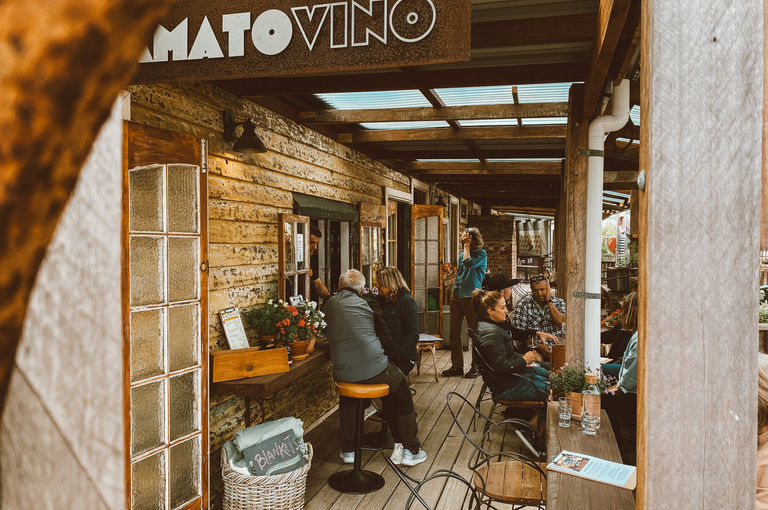 image of a deck with people sitting at tables and chairs, underneath a sign that says 'Amato Vino'.
