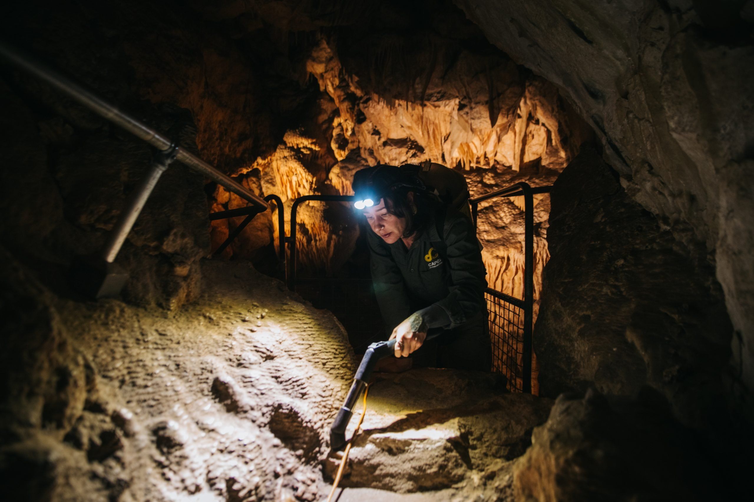 image of a person crouching in a cave vaccuuming dust