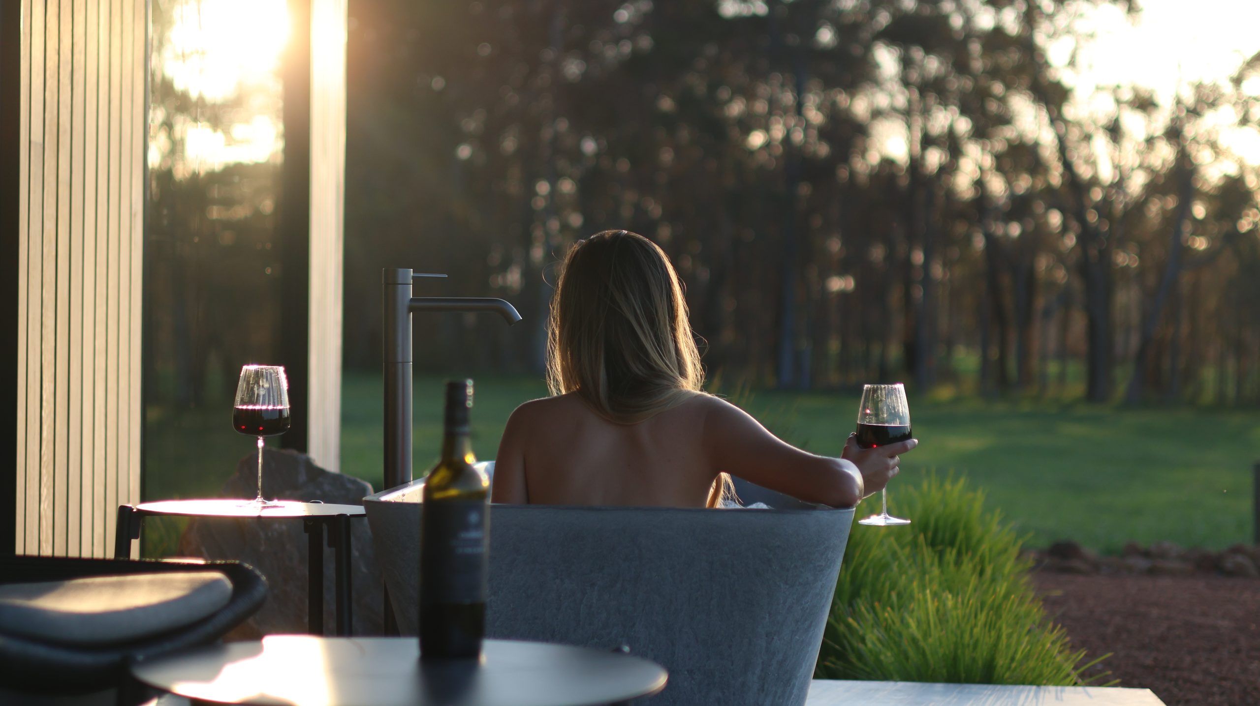 Women in outdoor bath with wine in hand, at the 8 Paddocks accommodation