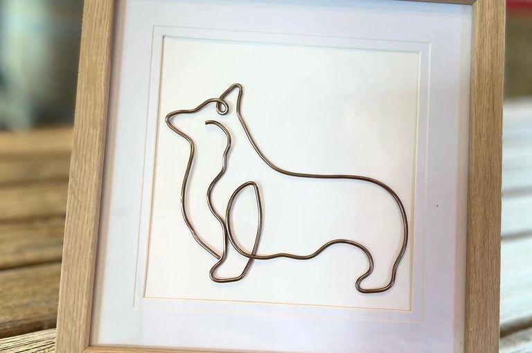 A wooden framed painting picturing the outlines of a dog