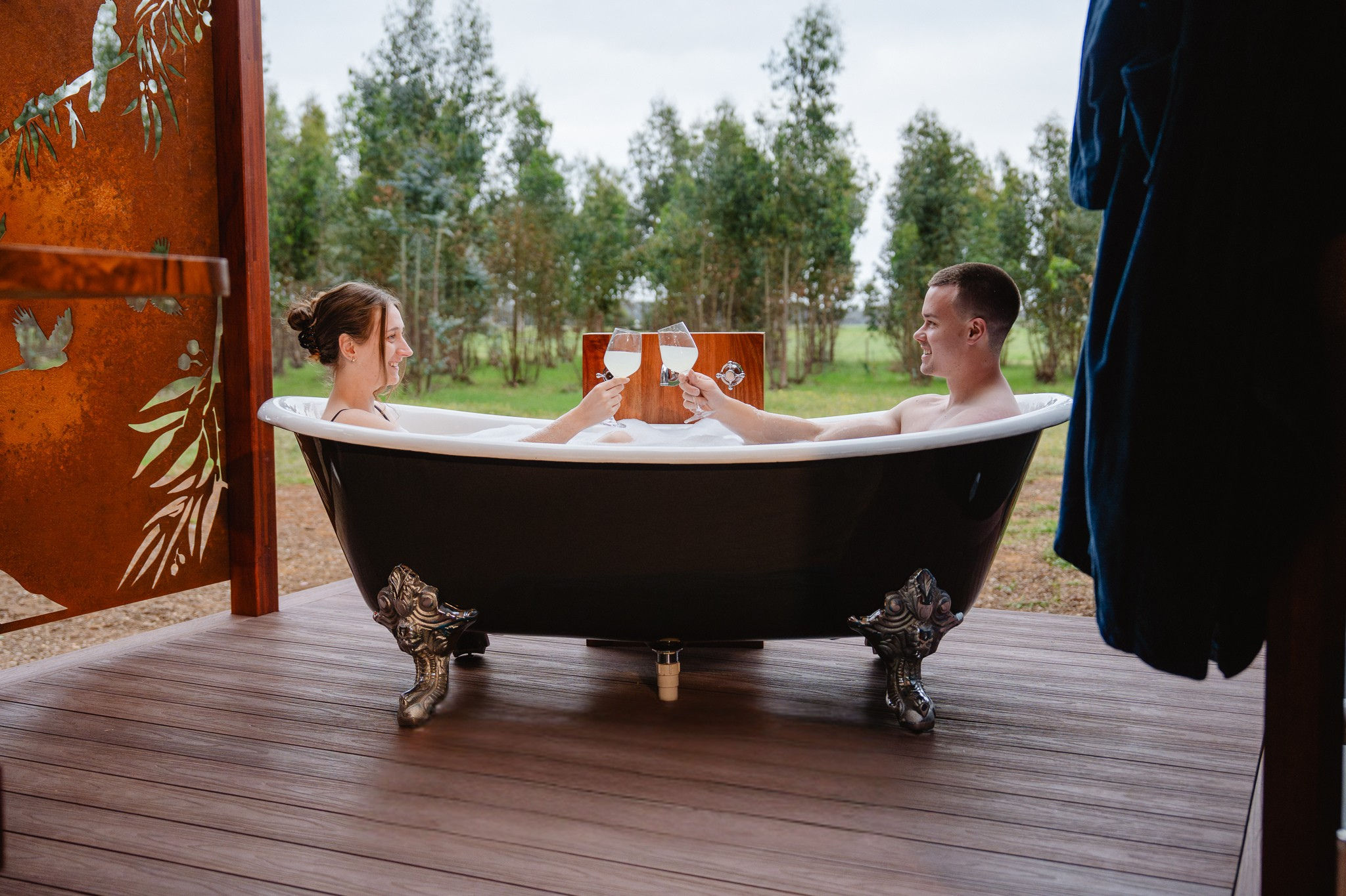 A couple in an outdoor bathtub at Tree Chalets