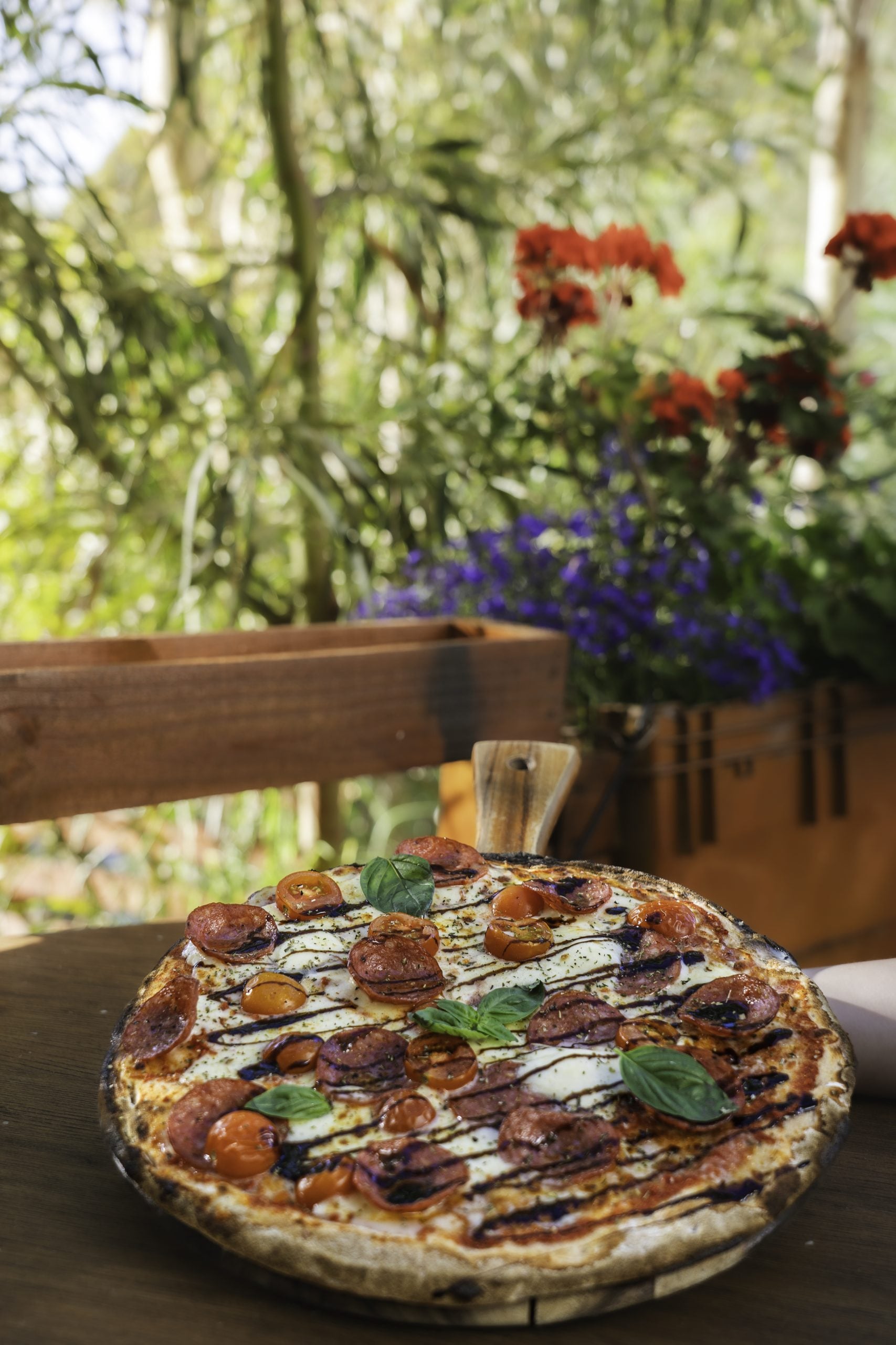 Pizza in front of vase of flowers.