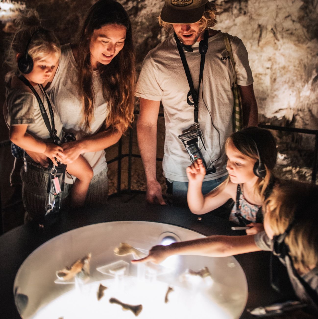 Family with audio players inside Mammoth Cave looking at megafauna fossils on display.