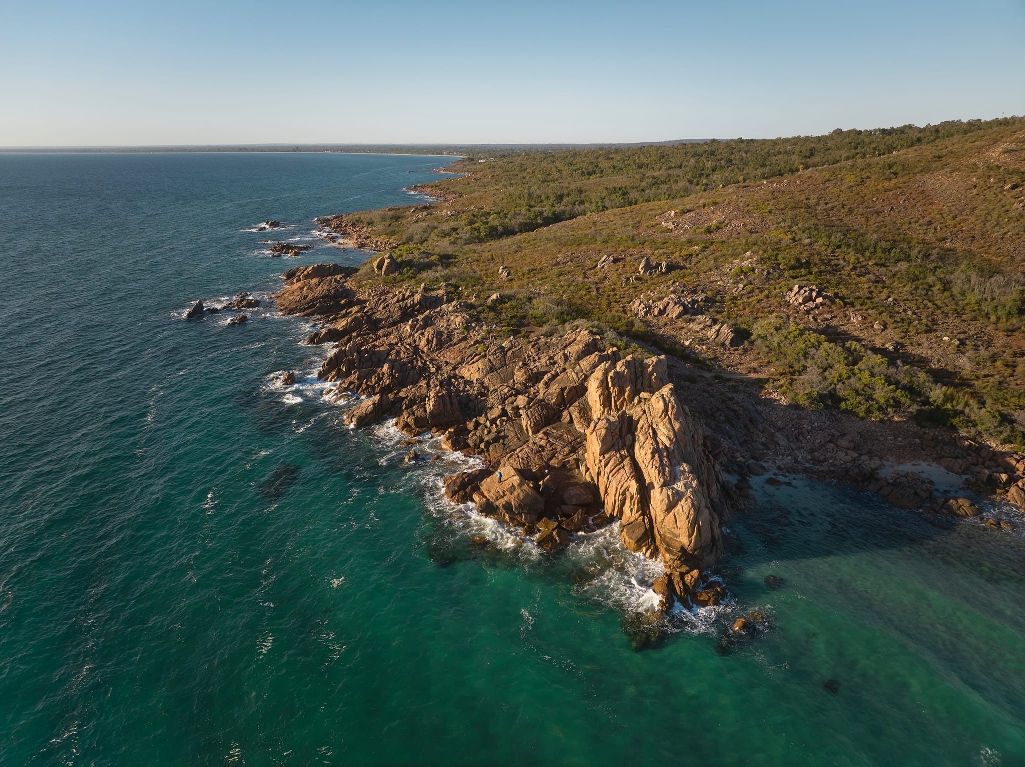 Castle Rock from far away with orange sunlight and blue ocean