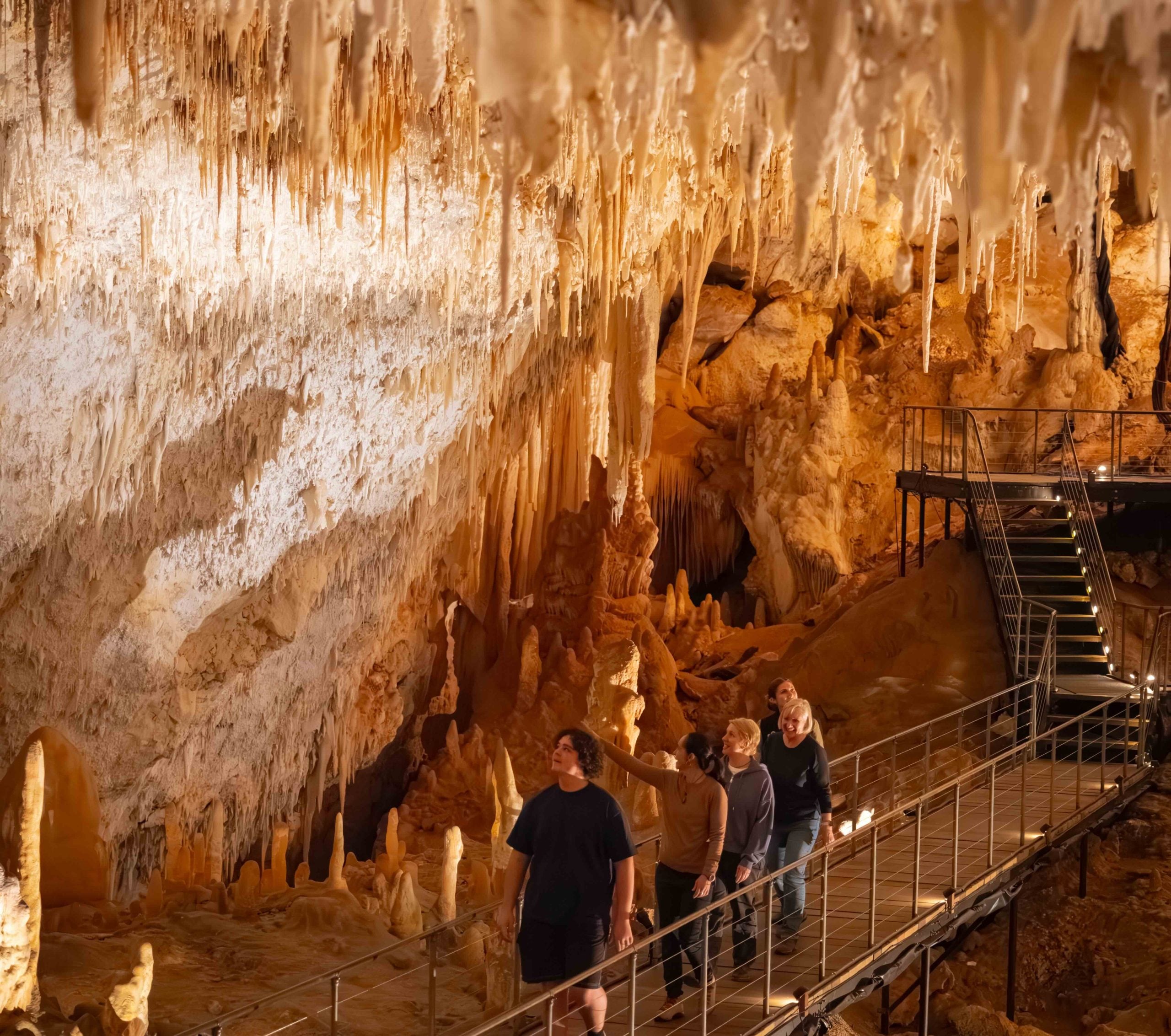 People walking through Jewel Cave, looking at different crystals which are called speleothems.