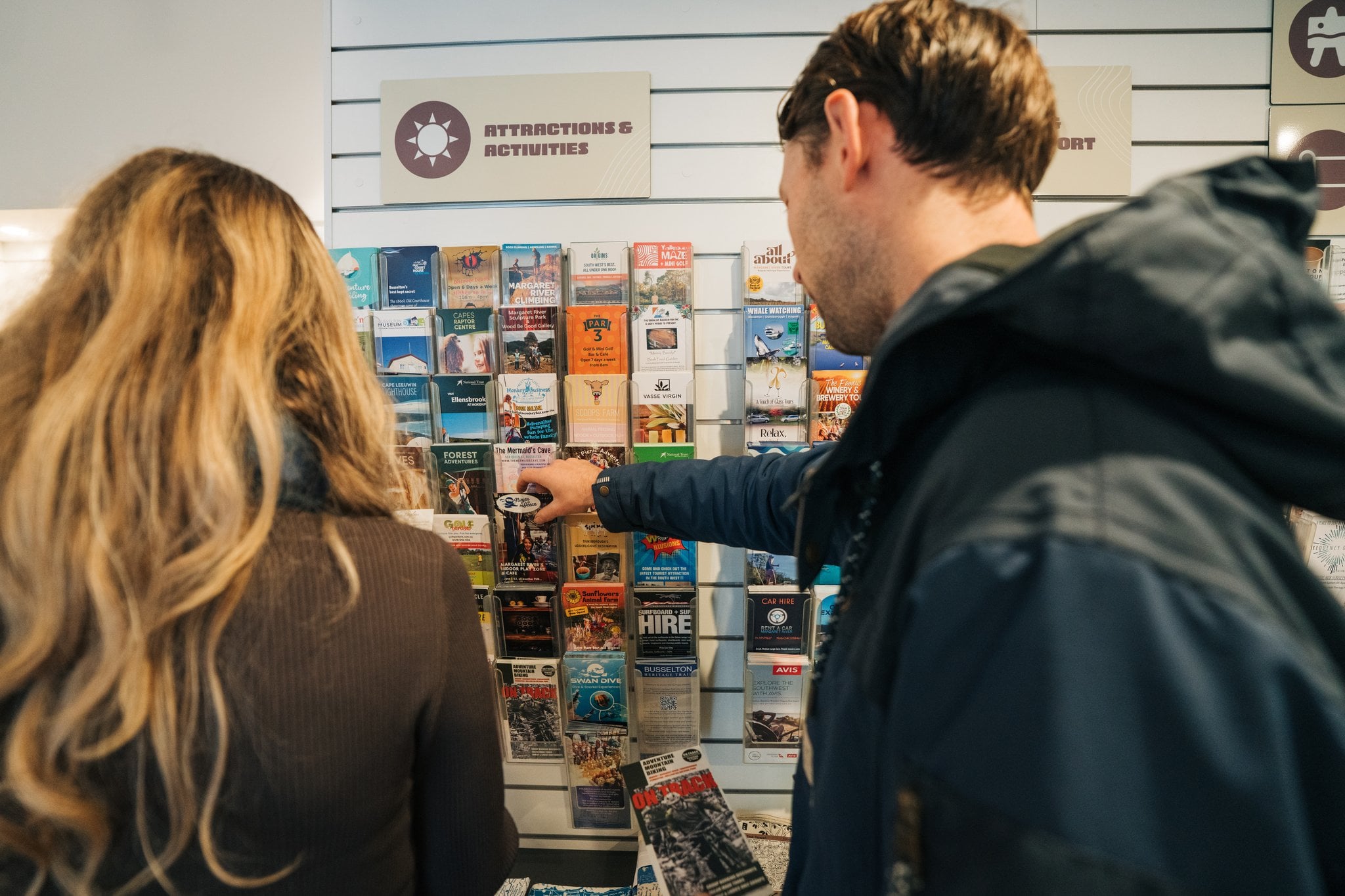 People looking at a brochure rack inside a building