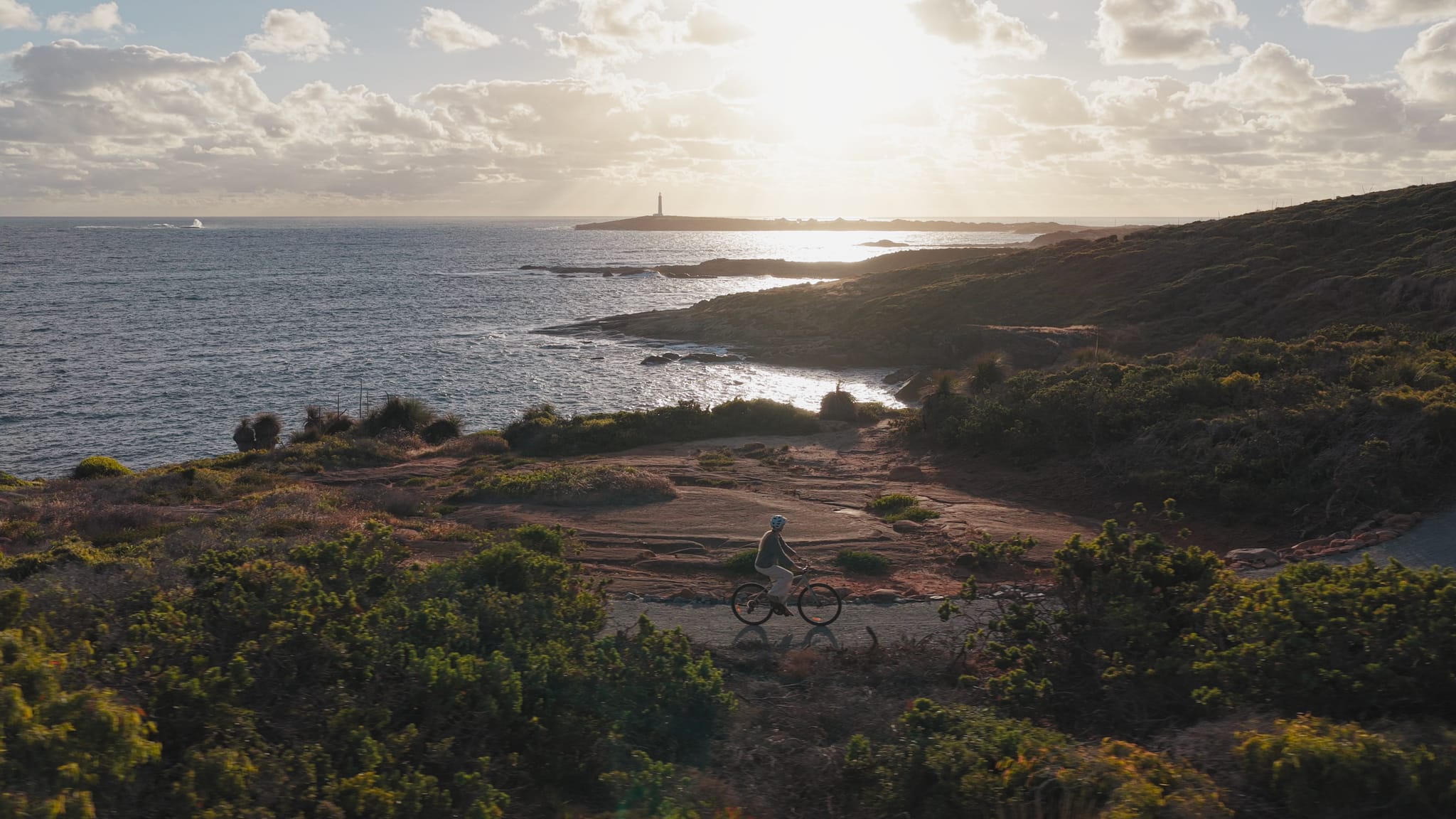 A person riding a bike along a coastal gravel path