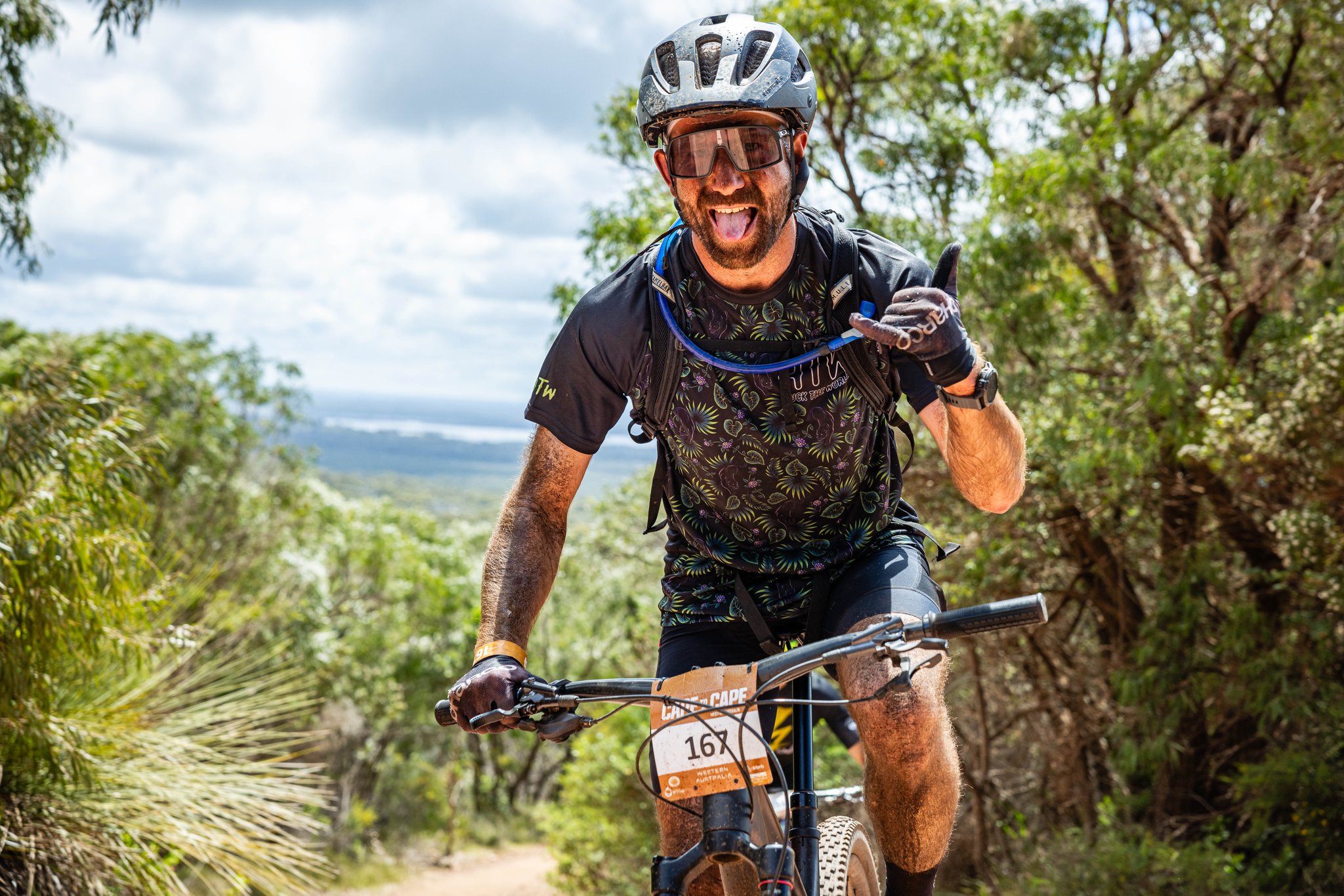 A person holding up a hand gesture while riding a mountain bike