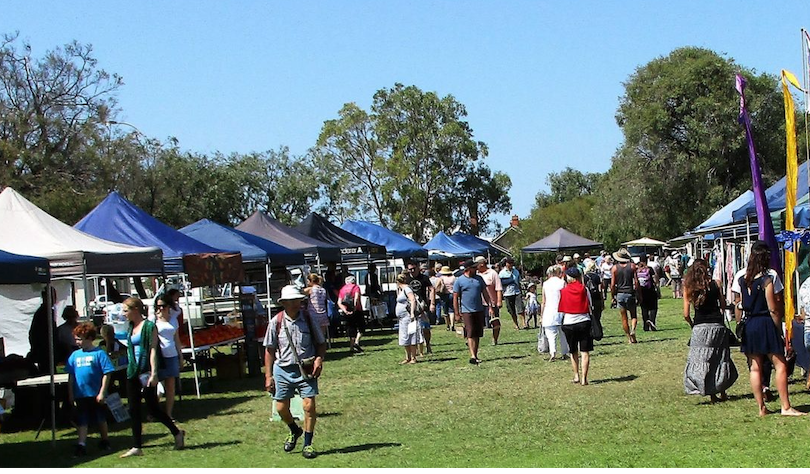 People walking around on a sunny day at market stalls